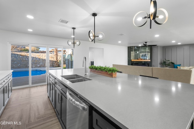 kitchen featuring pendant lighting, light parquet floors, ceiling fan with notable chandelier, dishwasher, and sink