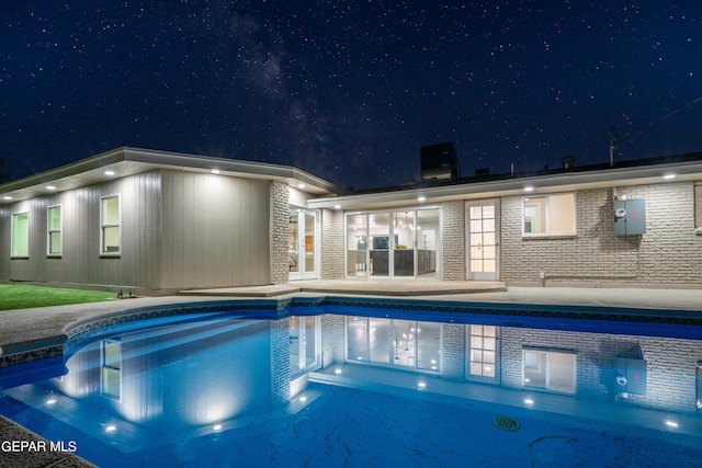 pool at twilight with a patio area