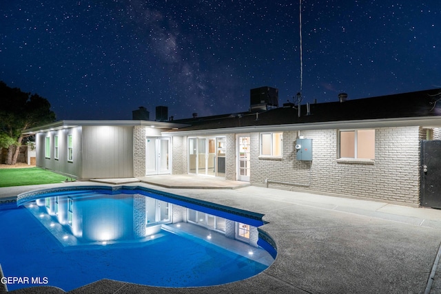 pool at night featuring a patio