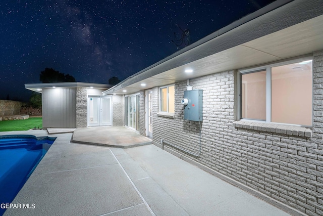 property exterior at night featuring a patio area