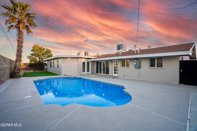 pool at dusk featuring a patio area