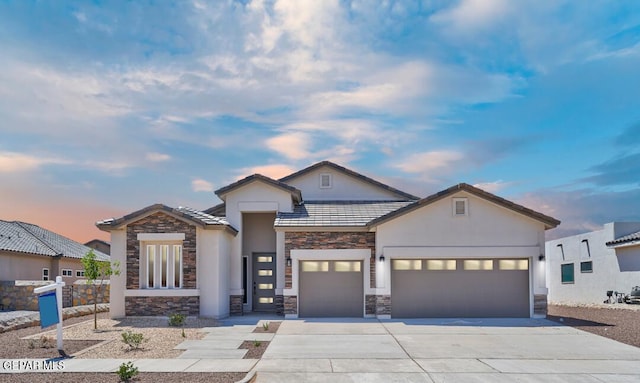 view of front of house with fence, stucco siding, driveway, stone siding, and an attached garage