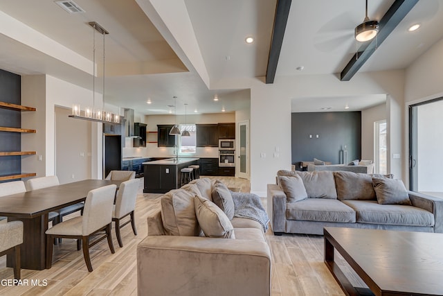 living room with visible vents, an inviting chandelier, light wood-style flooring, recessed lighting, and beamed ceiling