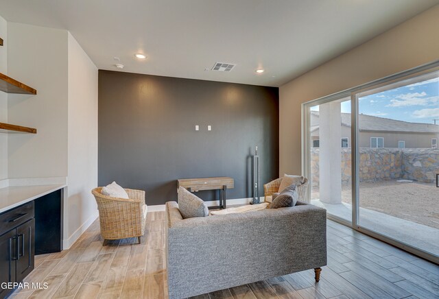 living room featuring baseboards, visible vents, and wood finish floors