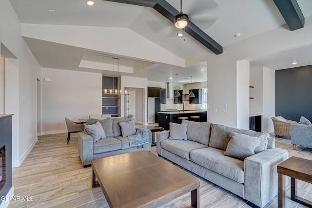 living area featuring recessed lighting, light wood finished floors, baseboards, ceiling fan, and vaulted ceiling with beams