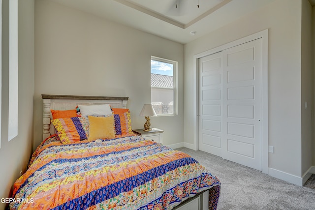 carpeted bedroom featuring baseboards and a closet