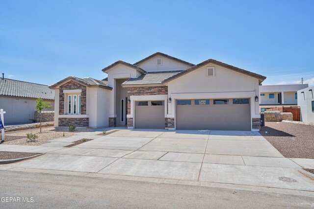 view of front of property with stone siding, stucco siding, an attached garage, and concrete driveway