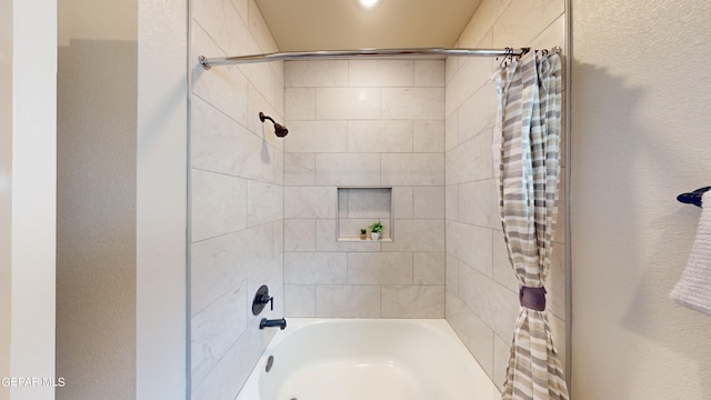 bathroom with a textured wall and shower / tub combo with curtain