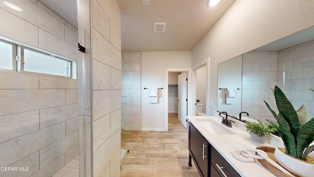 full bathroom with double vanity, visible vents, a sink, a shower stall, and baseboards