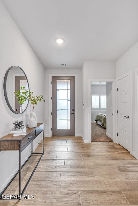 doorway to outside with baseboards, visible vents, and wood finish floors