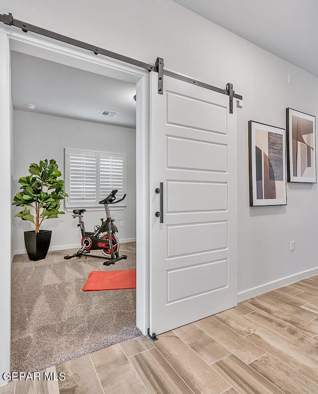 exercise area featuring wood finished floors, baseboards, and a barn door