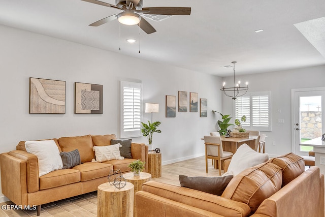 living room featuring a healthy amount of sunlight, ceiling fan with notable chandelier, and light hardwood / wood-style flooring