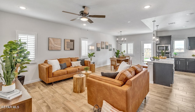 living room with sink, ceiling fan with notable chandelier, and light hardwood / wood-style flooring