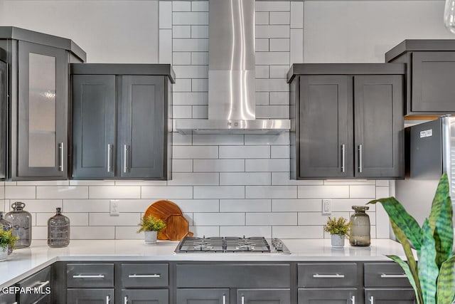 kitchen featuring backsplash, wall chimney exhaust hood, light countertops, and stainless steel appliances