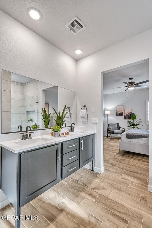 ensuite bathroom featuring double vanity, wood finish floors, a sink, and visible vents