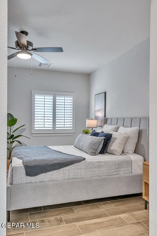 bedroom with a ceiling fan, wood tiled floor, and visible vents