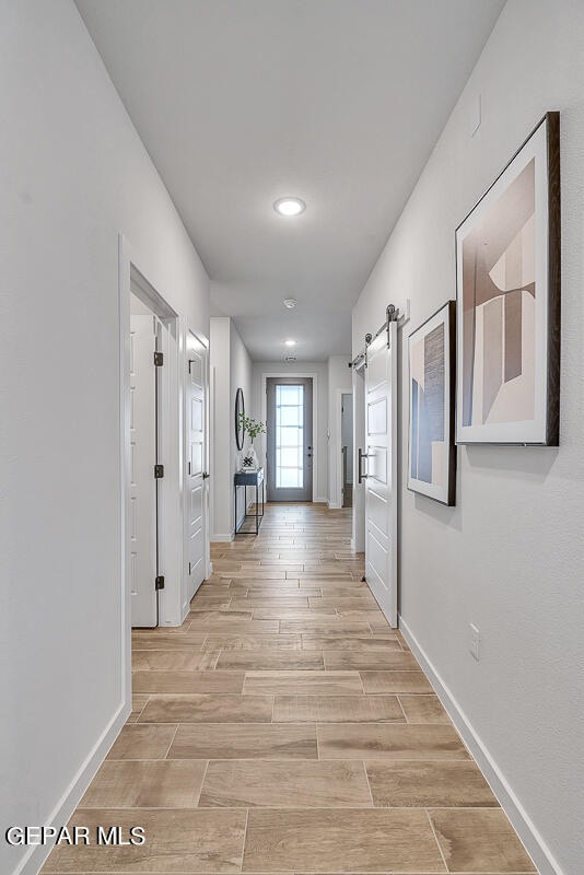 corridor with wood tiled floor, baseboards, and a barn door