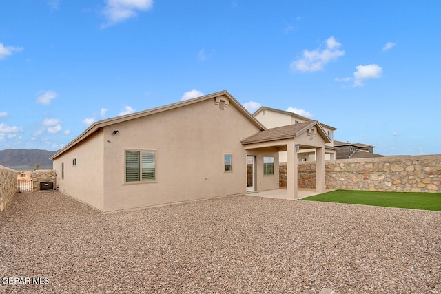 rear view of property featuring a mountain view, a fenced backyard, a patio, and stucco siding