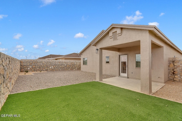 back of property with a yard, a fenced backyard, a patio, and stucco siding