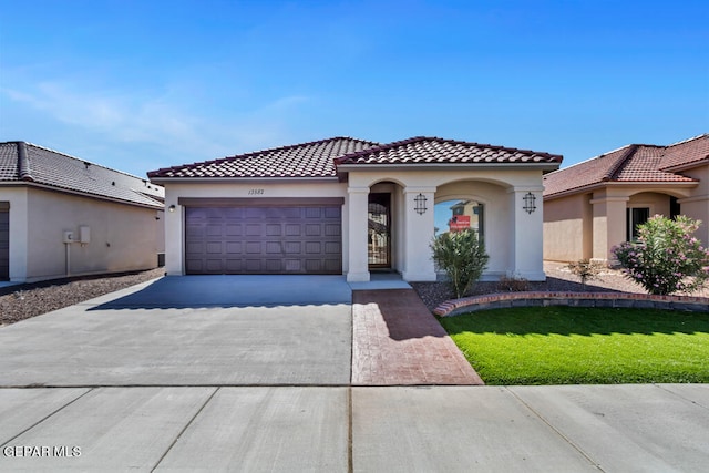 mediterranean / spanish home featuring a front yard and a garage