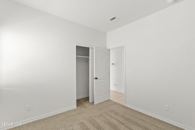 unfurnished bedroom featuring light colored carpet and a closet