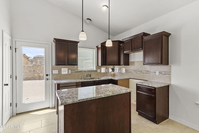 kitchen featuring a center island, sink, hanging light fixtures, light stone counters, and backsplash