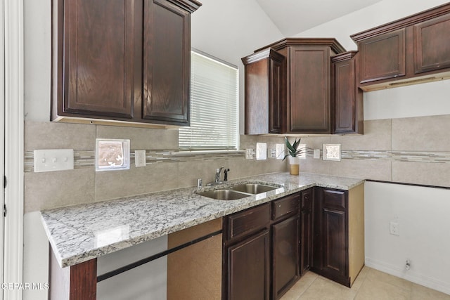 kitchen featuring dark brown cabinetry, sink, tasteful backsplash, light stone counters, and light tile patterned floors