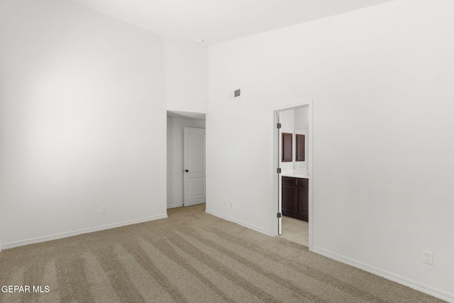 carpeted spare room with a towering ceiling