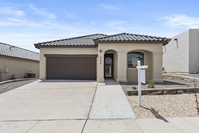 mediterranean / spanish-style home with central air condition unit and a garage