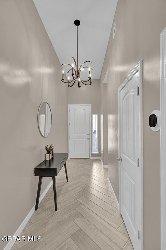 foyer with light parquet floors and an inviting chandelier