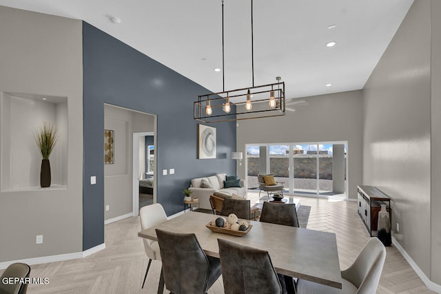 dining room with light parquet flooring, a chandelier, and a high ceiling