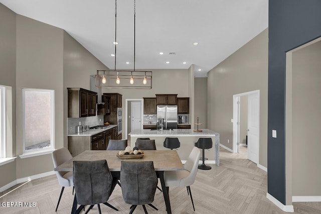 dining area with light parquet flooring, a high ceiling, and a chandelier