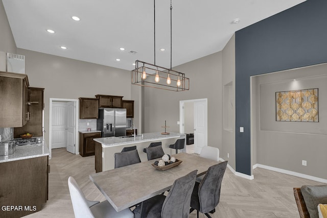 dining space with light parquet flooring, an inviting chandelier, sink, and a high ceiling