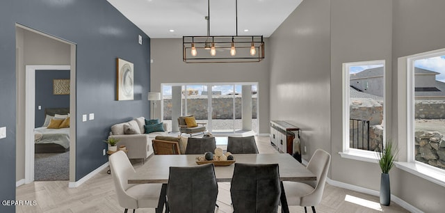 dining space with light parquet floors, a high ceiling, and a notable chandelier