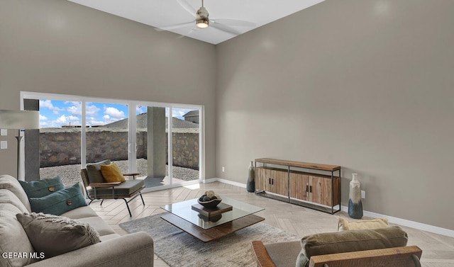 living room with light parquet floors, ceiling fan, and a towering ceiling