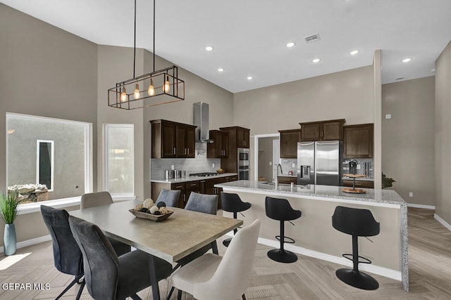 dining space featuring light parquet floors, sink, a chandelier, and a high ceiling