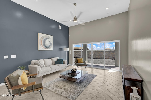 living room with ceiling fan, a high ceiling, and light parquet flooring