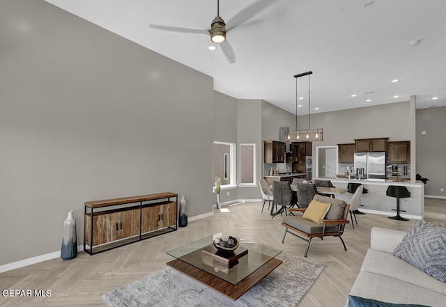 living room featuring light parquet flooring, ceiling fan, and a high ceiling