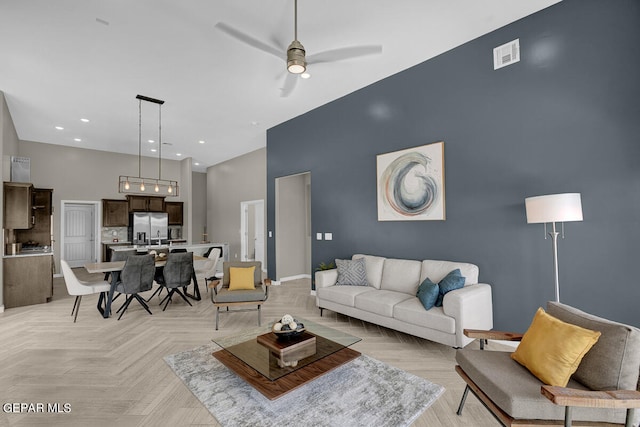 living room featuring light parquet flooring, ceiling fan, and a towering ceiling