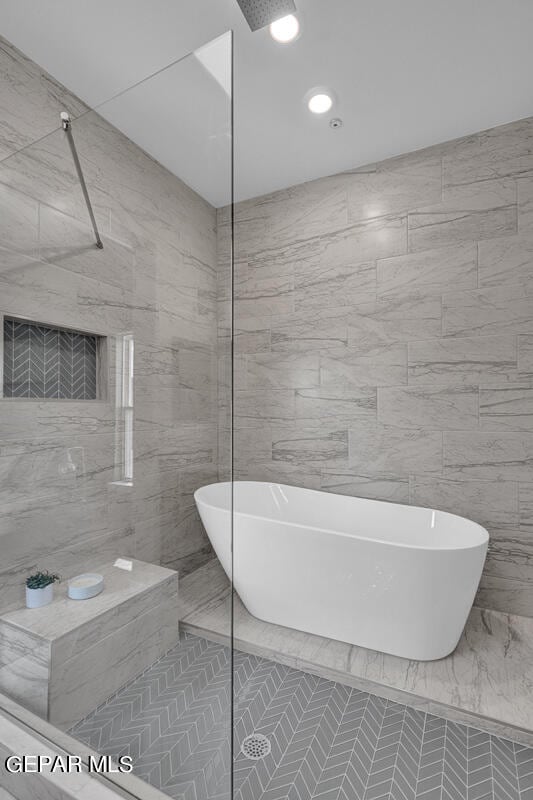 bathroom with a tile shower, tile floors, and tile walls