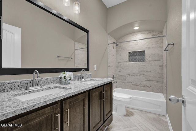 full bathroom with tiled shower / bath combo, double sink vanity, and toilet