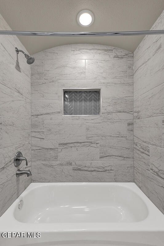 bathroom featuring tiled shower / bath combo and a textured ceiling