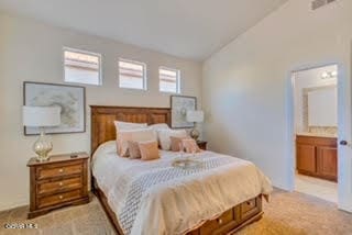 carpeted bedroom with ensuite bathroom and vaulted ceiling