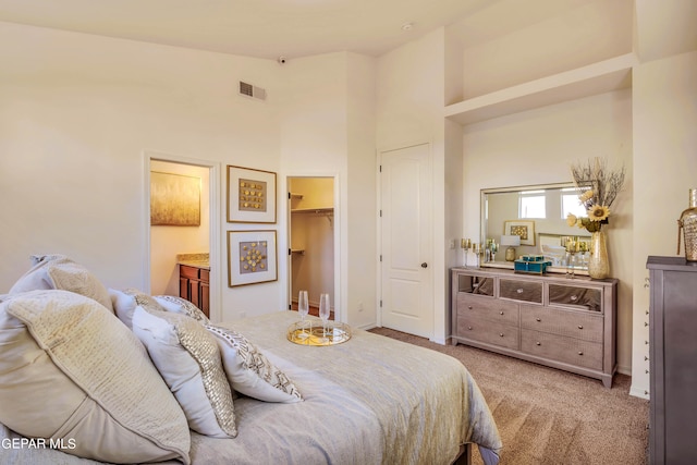 carpeted bedroom with a high ceiling, a walk in closet, and a closet