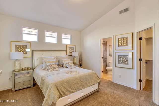 bedroom with ensuite bath, light colored carpet, a spacious closet, and vaulted ceiling