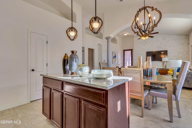 kitchen with light tile flooring, pendant lighting, a kitchen island, a chandelier, and light stone countertops