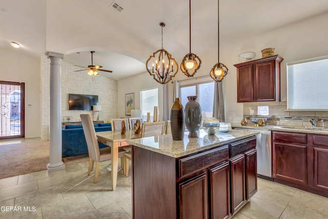 kitchen with light stone counters, ornate columns, decorative light fixtures, ceiling fan with notable chandelier, and a center island