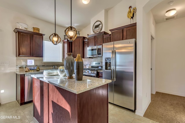 kitchen featuring tasteful backsplash, decorative light fixtures, appliances with stainless steel finishes, and light stone counters