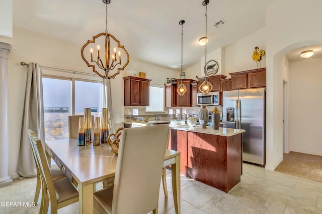 kitchen featuring light tile floors, pendant lighting, vaulted ceiling, and stainless steel appliances