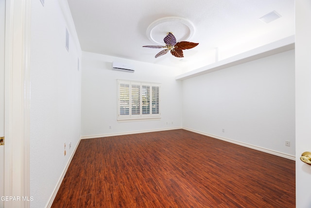 empty room with hardwood / wood-style floors, a wall unit AC, and ceiling fan